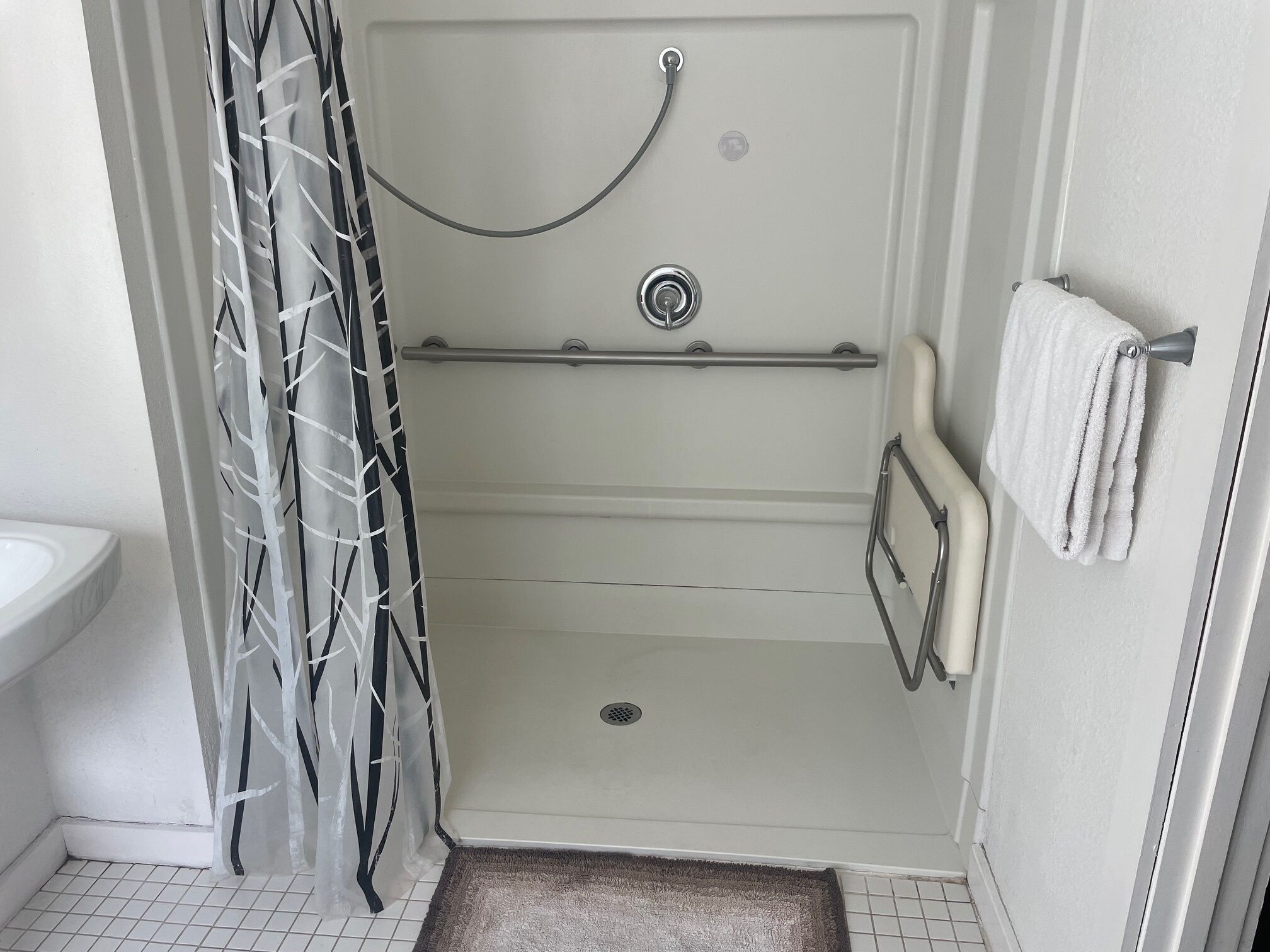 A bathroom with a shower, toilet, and a towel rack.