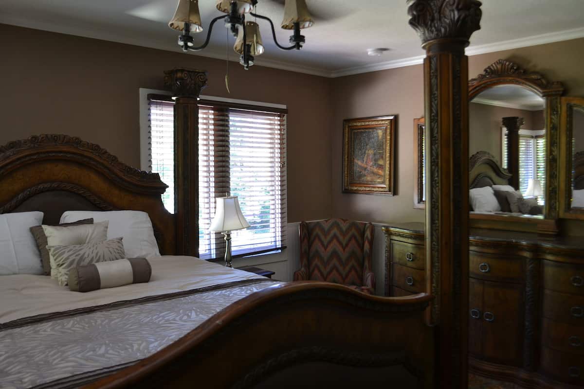 Une chambre à coucher avec un grand lit, une commode, une chaise et un miroir.