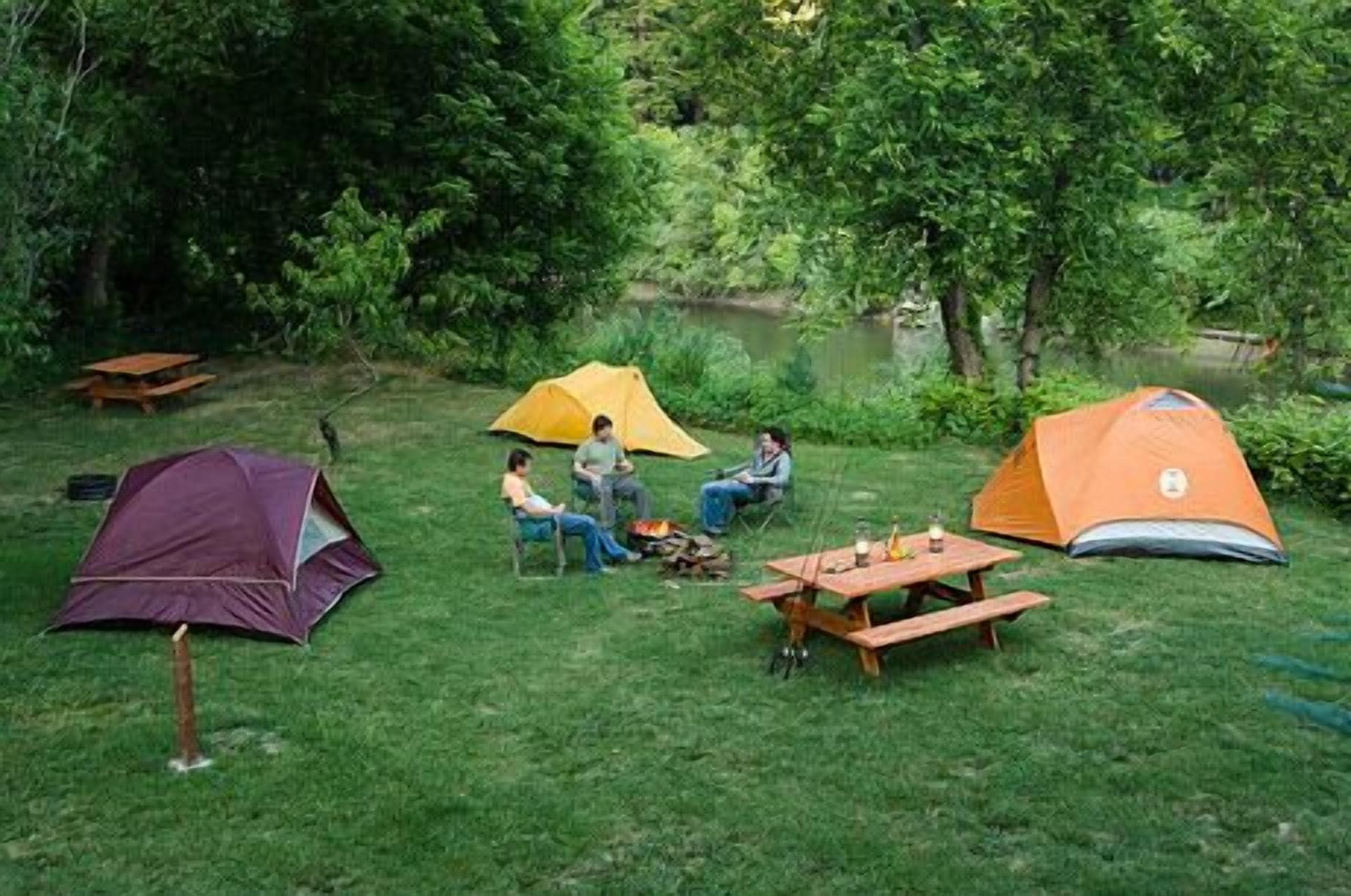 A campsite with tents, a picnic table, and a small fire pit.