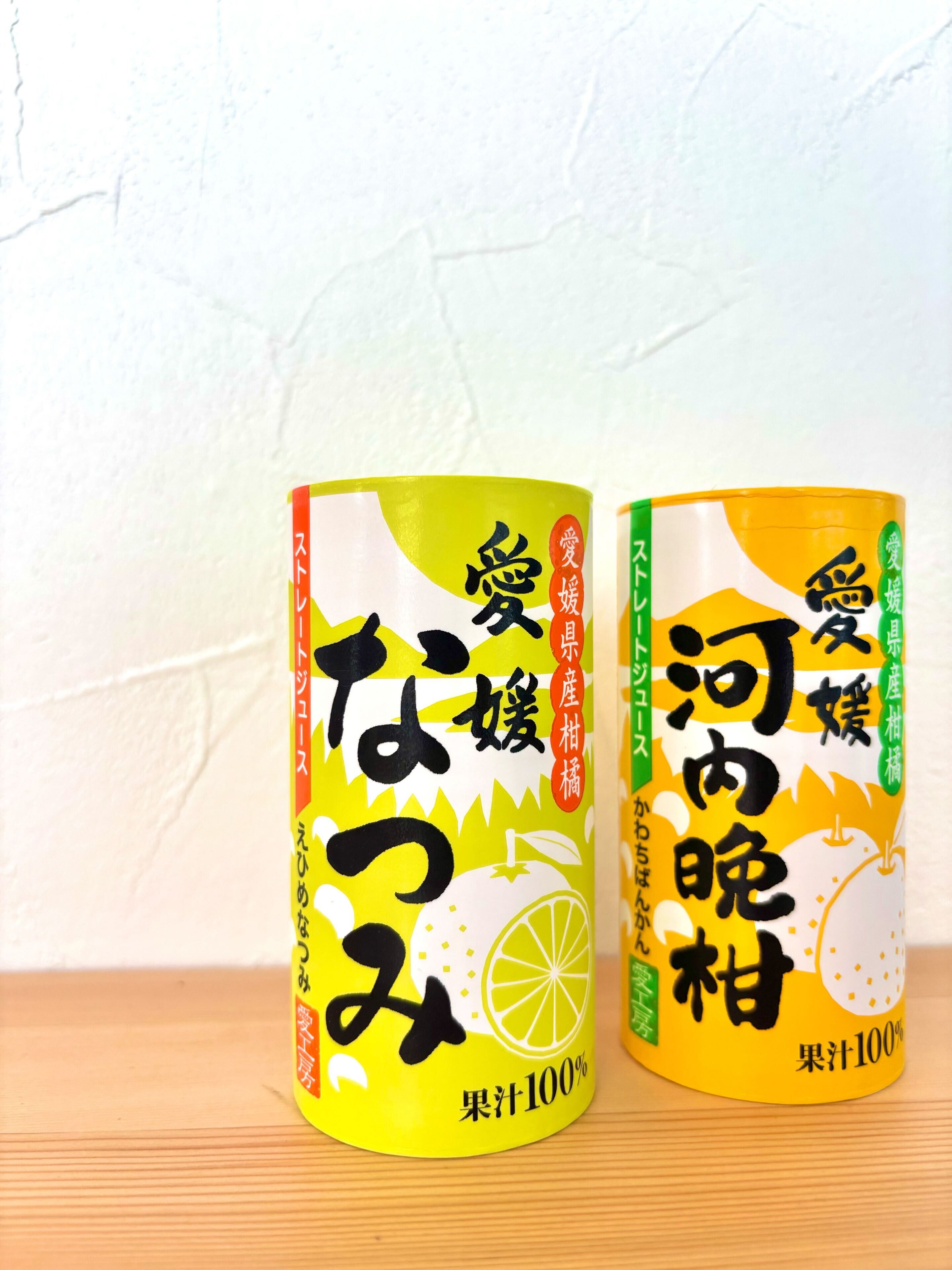 Dos recipientes cilíndricos con texto japonés e ilustración de una rodaja de limón, sobre una superficie de madera frente a una pared lisa.