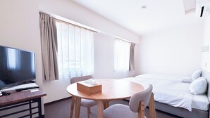 A hotel room with a bed, a TV, a desk with a remote control, and a chair. - Uwajima Oriental Hotel (Uwajima)