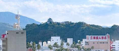 A cityscape with modern buildings, a traditional pagoda, and a prominent red sign.