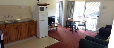 A compact living space with a kitchenette, a dining area, and a seating area with a sofa and chairs.