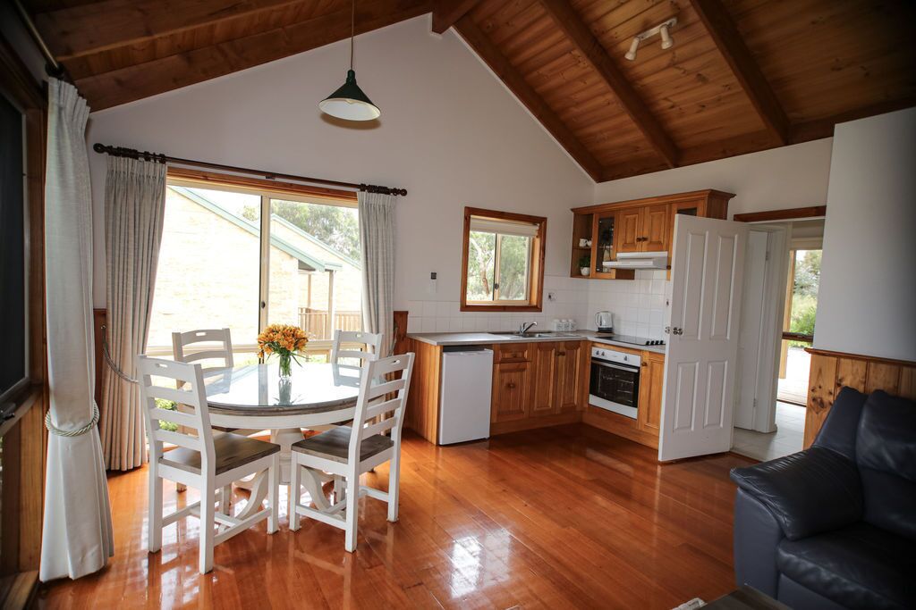 A kitchen with wooden cabinets, a dining table with chairs, and a large window.