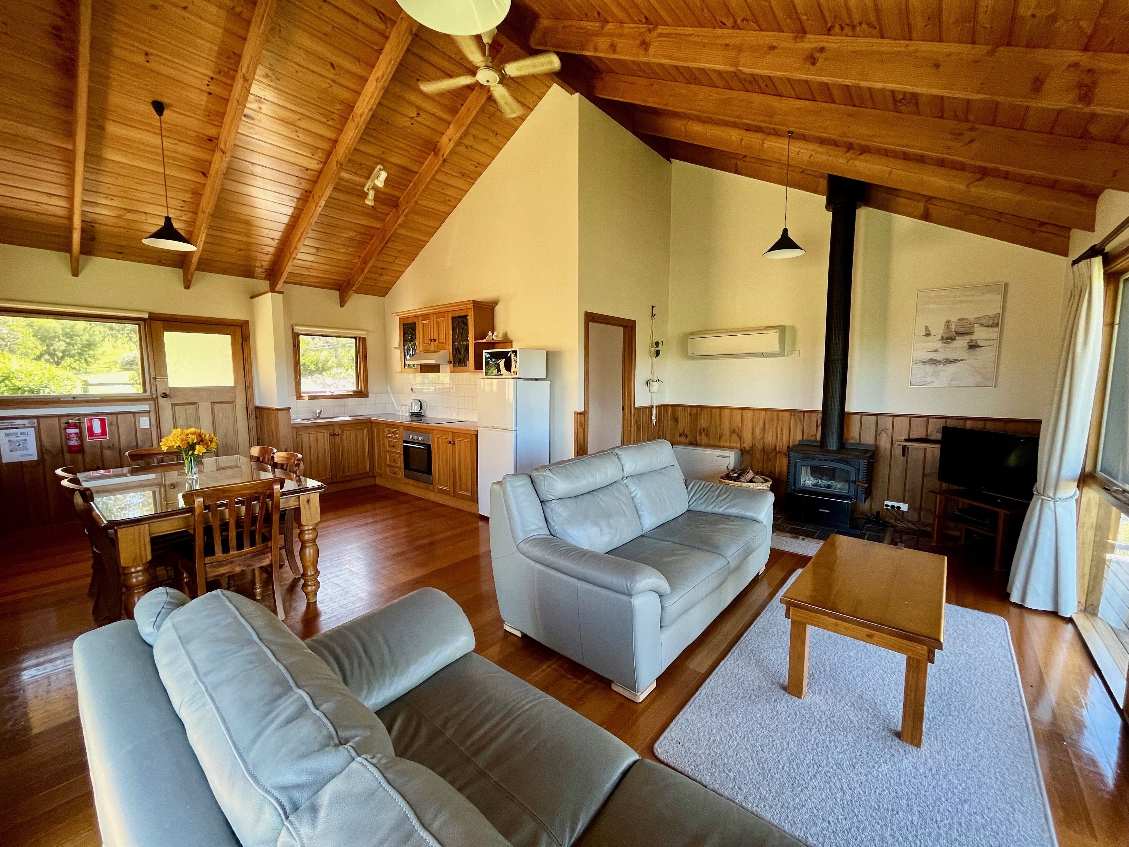 A spacious living area with a high ceiling, wooden beams, a sofa, a coffee table, and a fireplace.