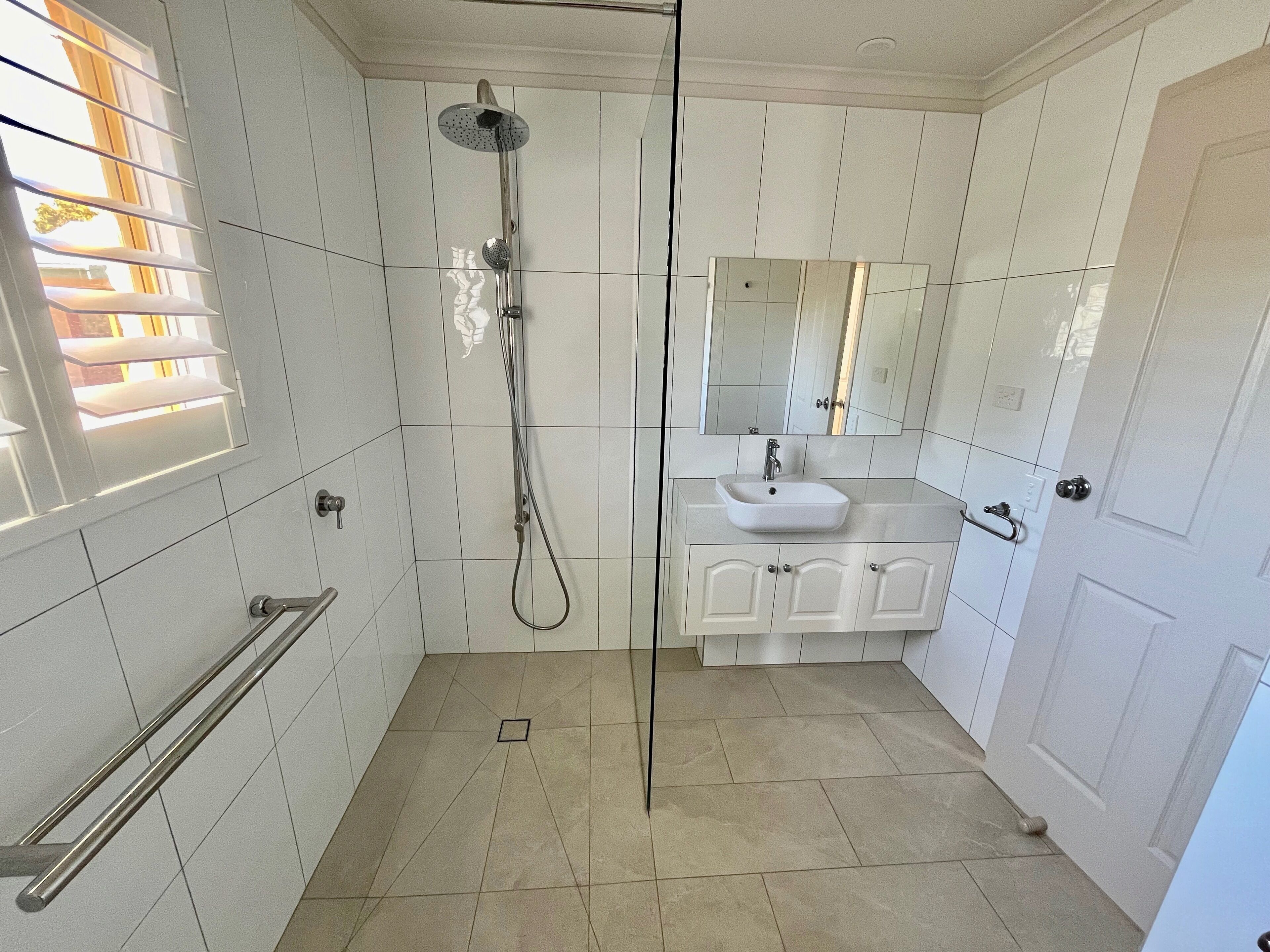 Ein Badezimmer mit Dusche, Waschbecken und Spiegel.
