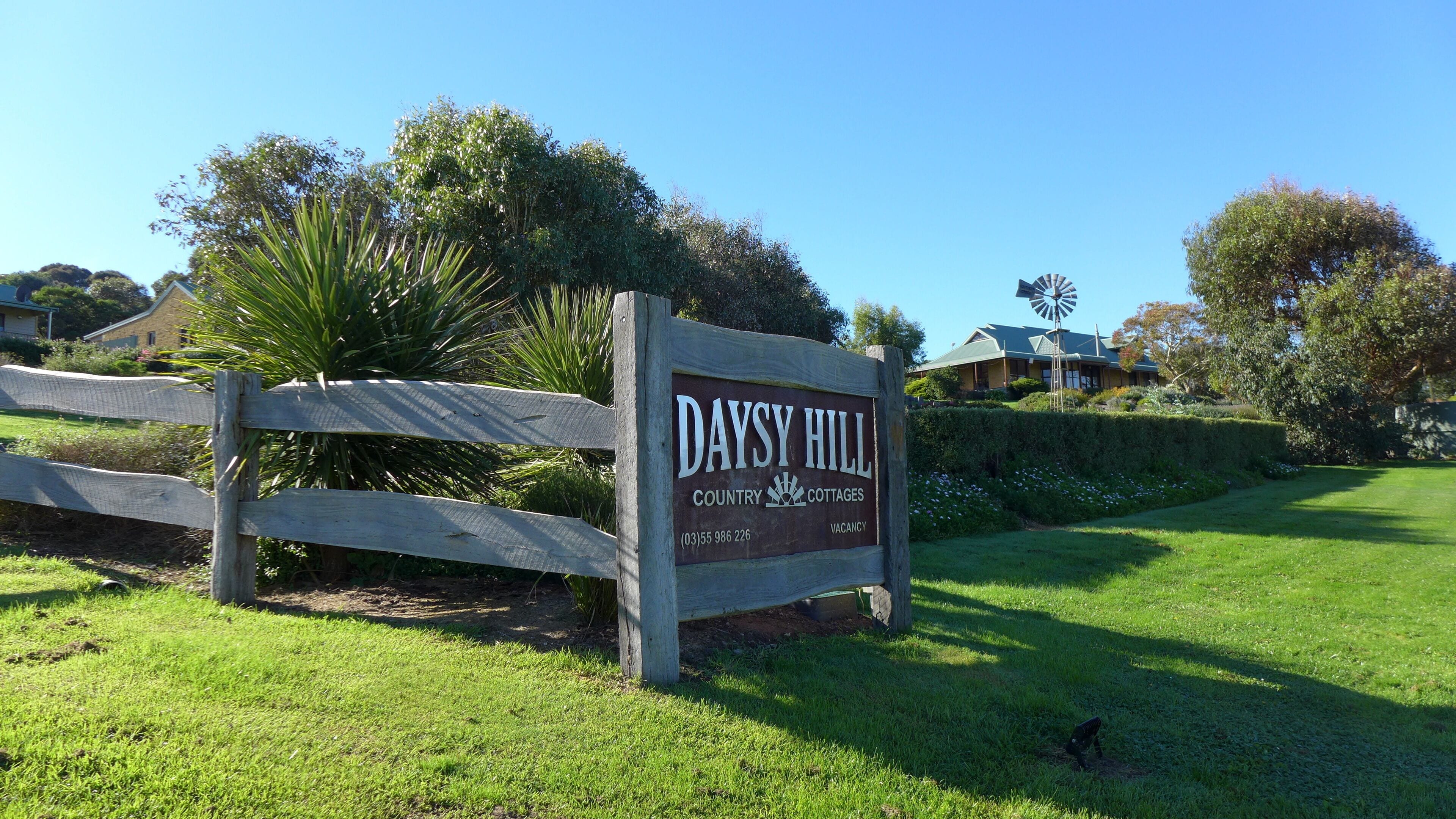 A wooden sign for Daysy Hill Country Cottages with a contact number and a 'Vacancy' label.