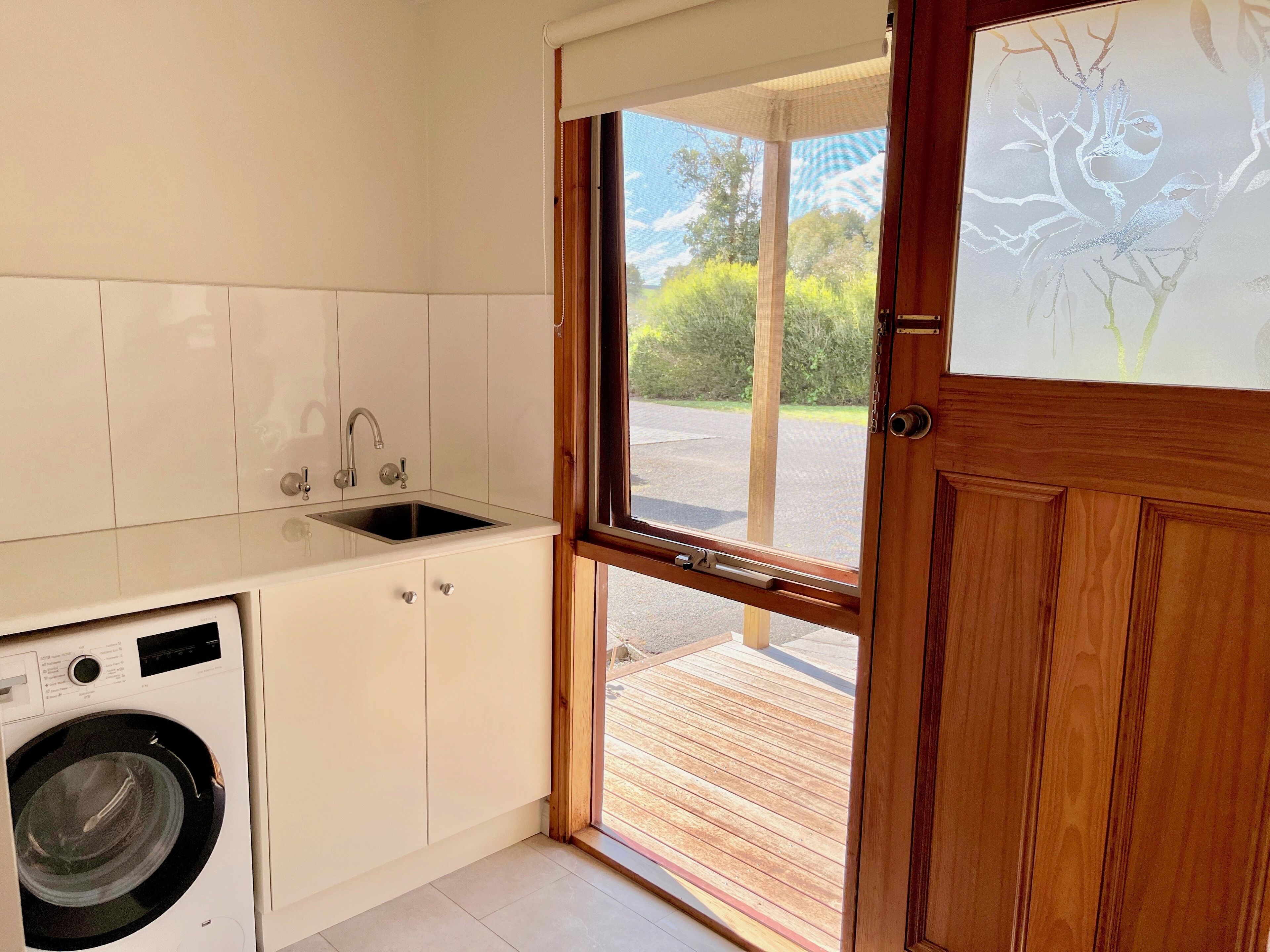 Cocina compacta con lavadora integrada, un lavamanos y una ventana con vistas al exterior.