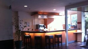 A bar area with a counter, stools, and a television. - Au Relais de Clamart (Clamart)