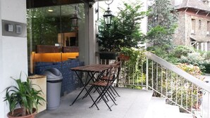 A balcony with a table and chairs, a trash bin, and potted plants. - Au Relais de Clamart (Clamart)