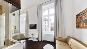 Una camera d'albergo moderna con un letto, una televisione, un divano e un'ampia finestra con tende.
