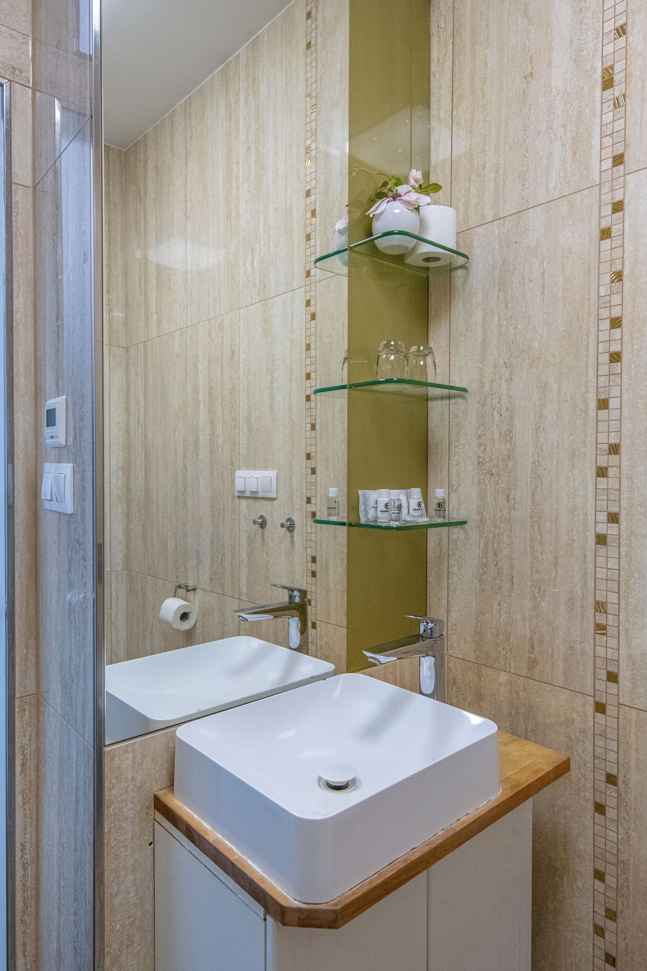 A bathroom with two sinks, a mirror, and shelves with toiletries.