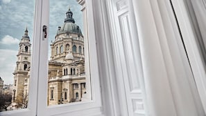 A view through a window of a historic building with a prominent dome and adjacent towers.
