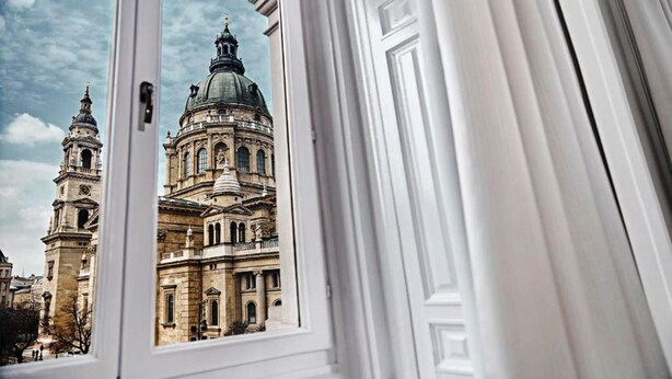 A view of a historic building with a large dome and bell towers through a window with white trim. - Andrassy Thai Hotel (Budapest)