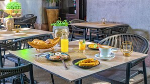 A table set with breakfast items, a basket, and a vase with greenery. - Andrassy Thai Hotel (Budapest)