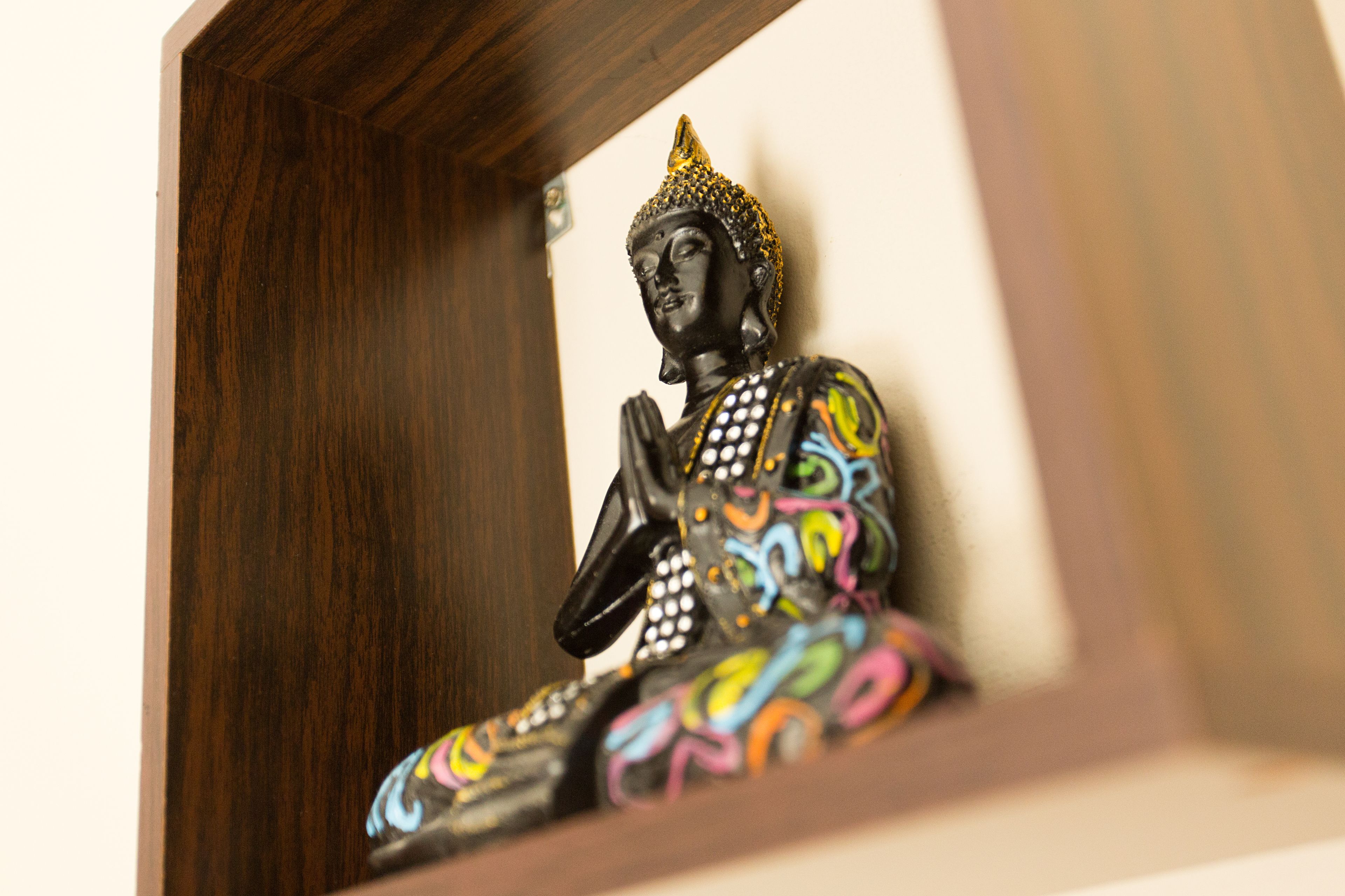 Una estatua de Buda con diseños coloridos, ubicada en un marco de madera.