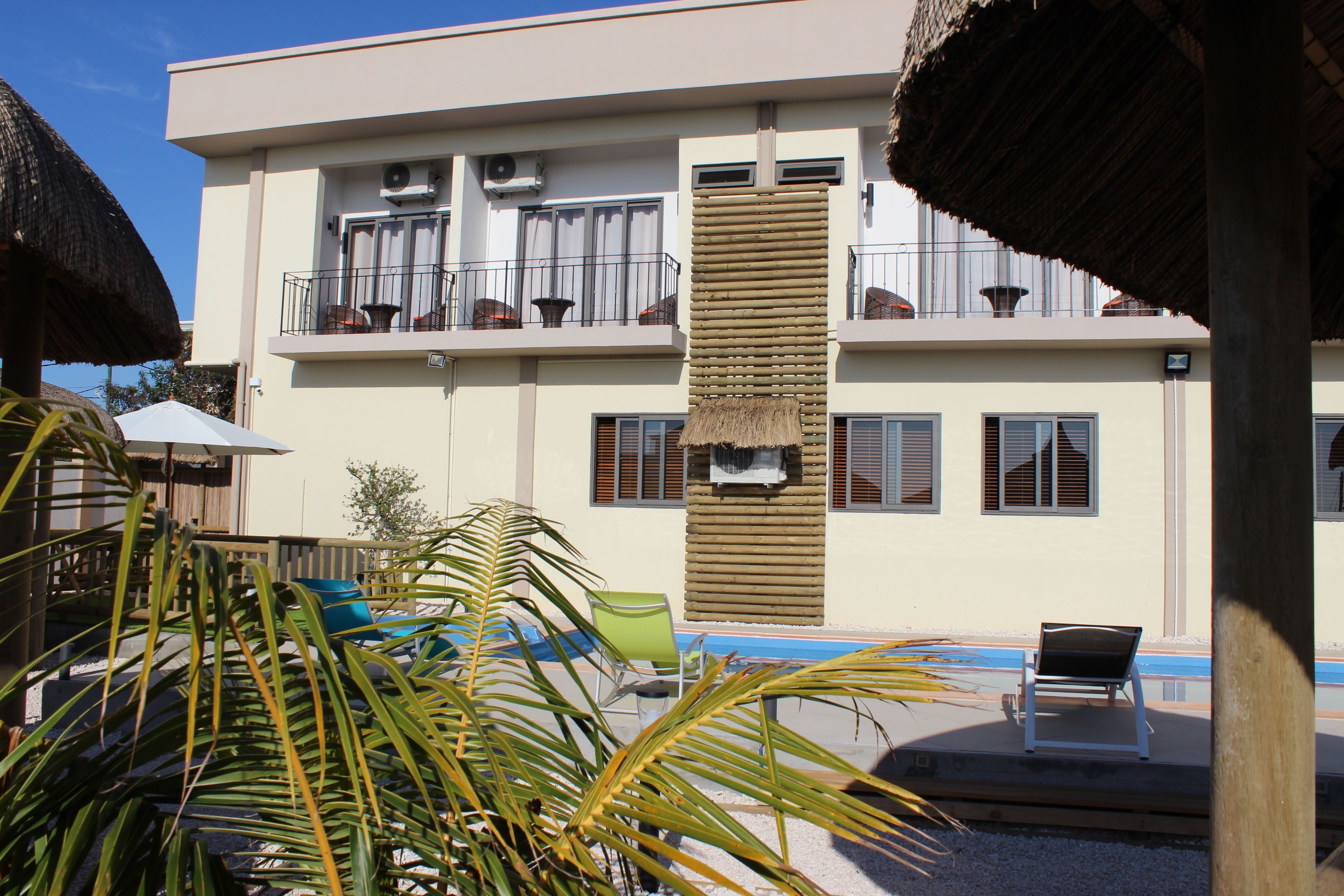 A two-story building with balconies, a pool, and outdoor seating.
