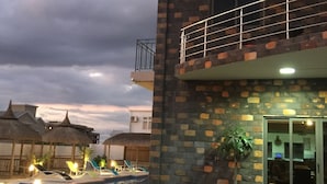 A two-story building with a balcony, a swimming pool, and a well-lit entrance. - L'Oiseau de l'Océan (Flic-en-Flac)