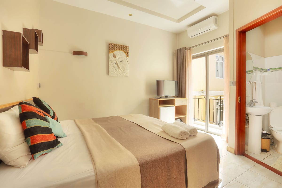 Ein Hotelzimmer mit Bett, Fernseher, Bad und Balkon.