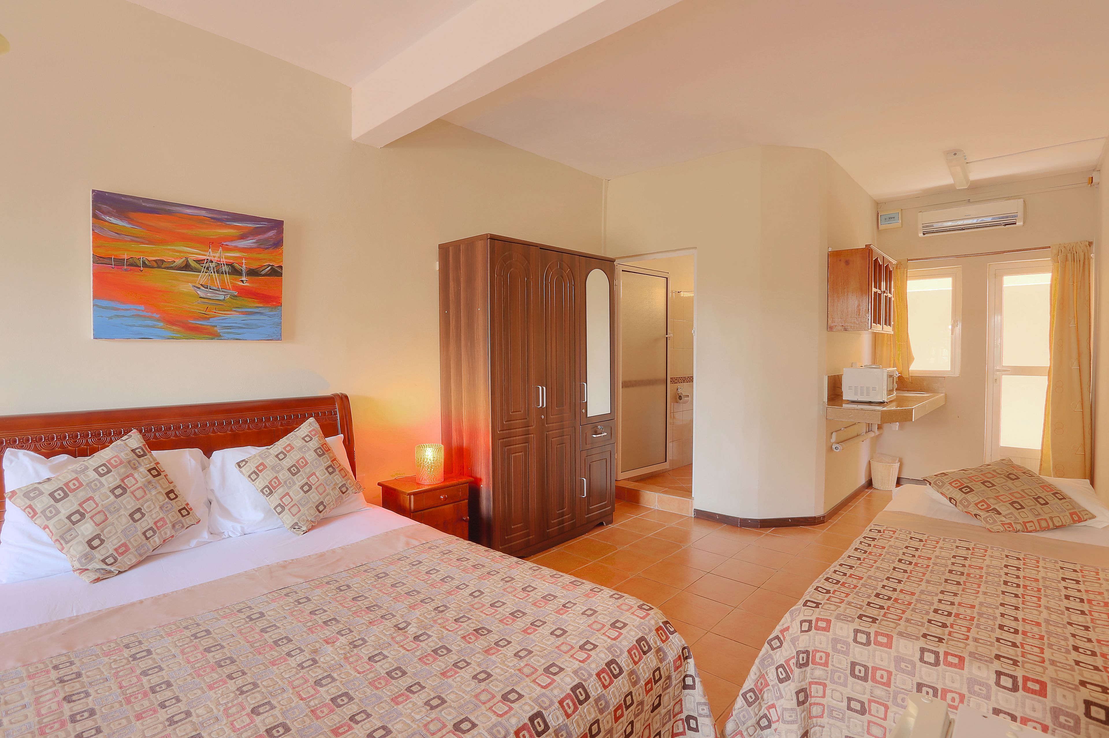 Une chambre d’hôtel avec deux lits, une armoire, une salle de bain et un tableau au mur.