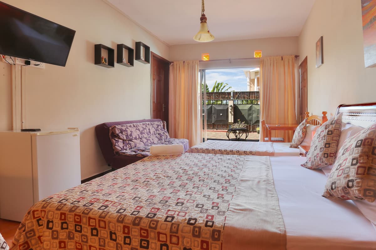 Ein Hotelzimmer mit Bett, Schreibtisch, Fernseher und Blick ins Freie.