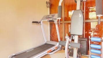 A gym with a treadmill, weight bench, and various exercise equipment.