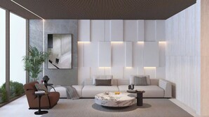 Een moderne woonkamer met een bank, fauteuil, salontafel en een groot abstract schilderij aan de muur.