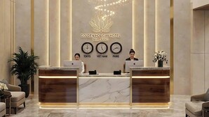Een receptiebalie in een hotel met een modern design, voorzien van een logo, klokken en een kroonluchter.