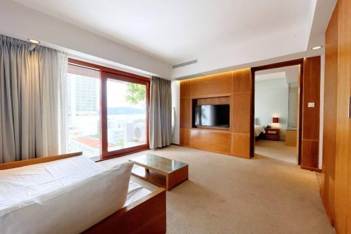 Hotelkamer met een bed, een televisie, een bank, een salontafel en uitzicht op de omgeving.
