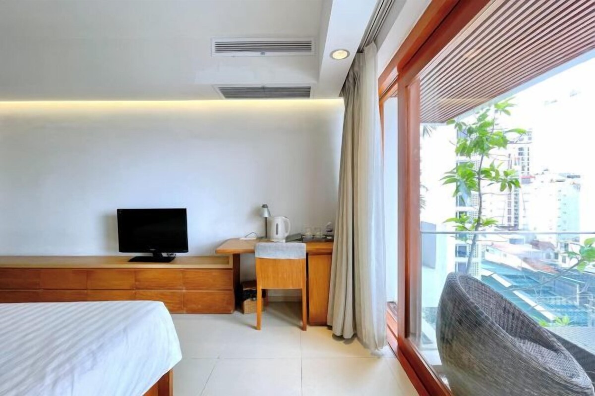 Una habitación de hotel con cama, escritorio, televisor y vistas a la ciudad.