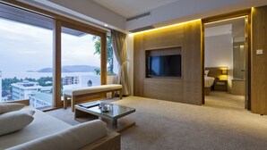Een moderne hotelkamer met een groot raam, een flatscreen televisie, een bank, een bijzettafeltje en een houten accentmuur.