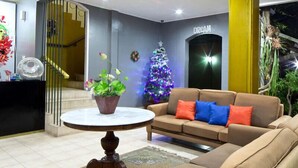 Una sala de estar con un sofá, una mesa de centro, una planta en maceta y un árbol de Navidad.
