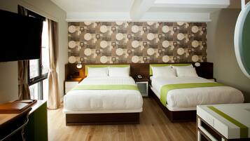 A hotel room with two beds, a desk, a TV, and a patterned wall.