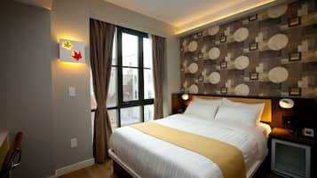 A hotel room with a large bed, a television, a window with curtains, and a wall with a geometric pattern.