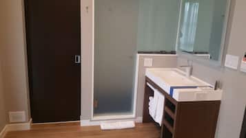 Un baño con una puerta oscura, un lavamanos blanco, un espejo y una toalla en el suelo.