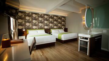 A hotel room with two beds, a bedside table, a small desk, a mirror, and a bathroom with a sink.