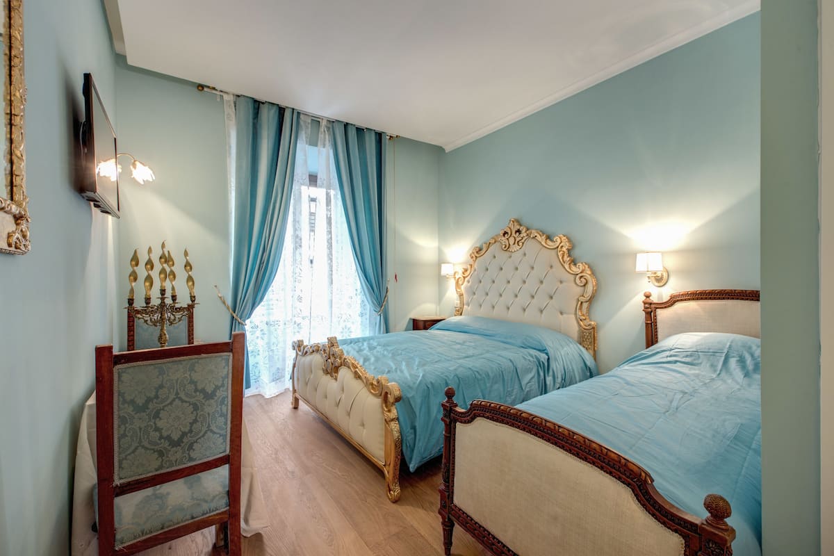 A bedroom with two beds, a chandelier, and a mirror.