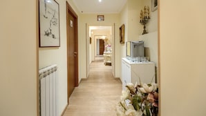 A hallway with a radiator, framed artwork, a candelabra, and a table with glasses. - La Reggia dei Principi (Rome)