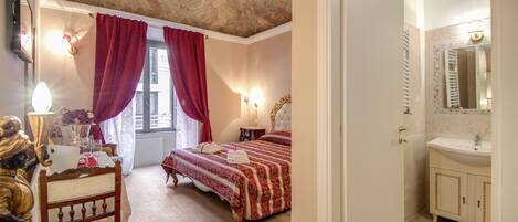 A bedroom with a bed, a nightstand, a lamp, and a window with curtains.