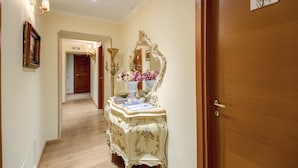 A hallway with a wooden door, a mirror, and a table with a vase of flowers. - La Reggia dei Principi (Rome)