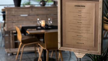 A framed menu board with an evening menu listing various dishes and their prices.