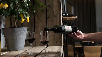 A wooden table with two wine glasses and a bottle of wine being poured into one of them.