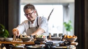 Un chef préparant des plats derrière un comptoir, avec différents bols et ustensiles de cuisine à portée de main.