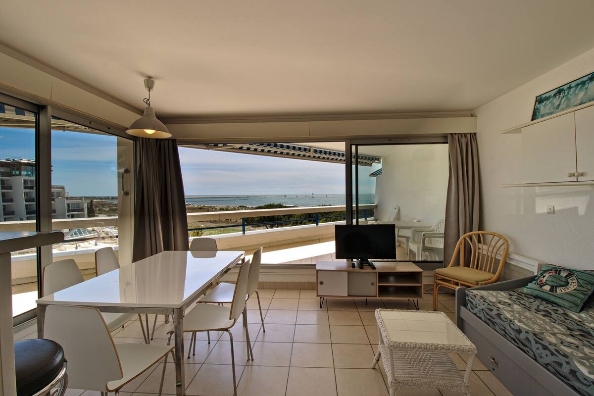 A modern living room with a balcony, a dining area, and a TV.