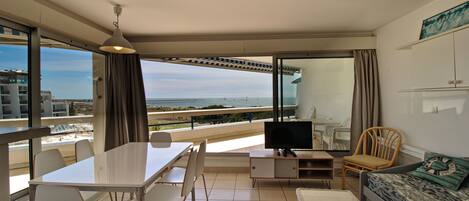 A modern living room with a balcony, a dining area, and a TV.