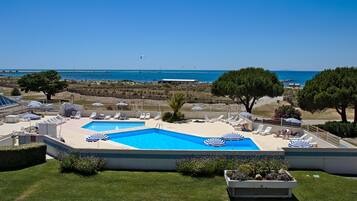 Una piscina al aire libre de temporada, sombrillas, tumbonas