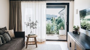 A modern living room with a sofa, a small table with a vase, and a TV on a wooden cabinet. - The Oaks Ranch (Mossy Point)