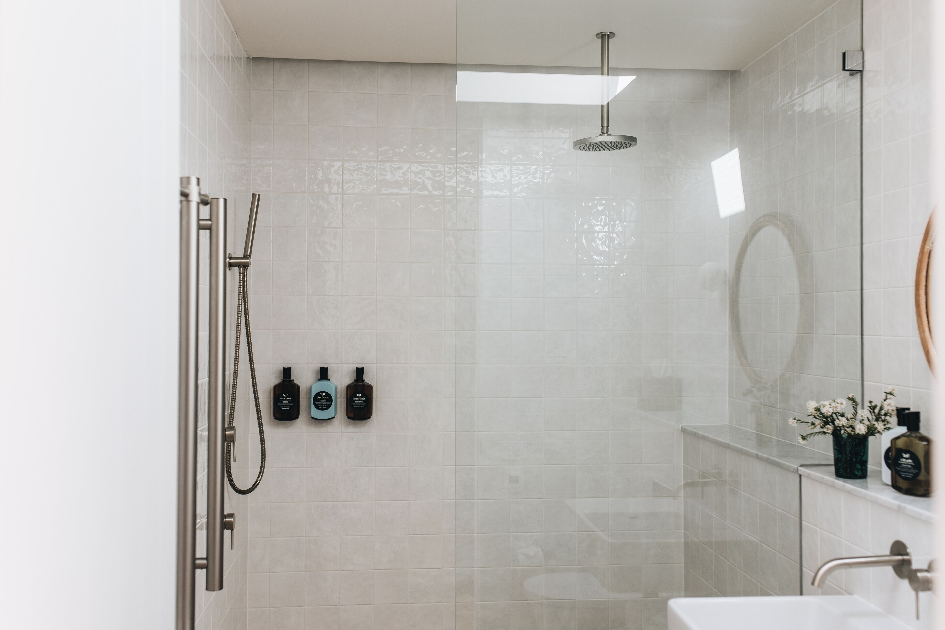 Un baño moderno con cabina de ducha de vidrio, un lavamanos blanco y un espejo.