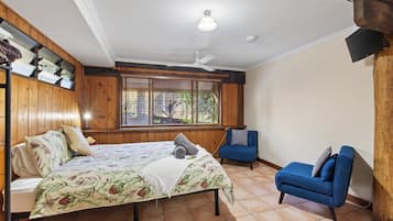 A bedroom with a bed, a chair, a window with blinds, and a ceiling fan.