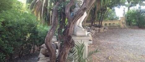 A statue surrounded by trees and a gravel path.